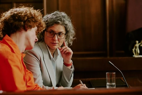 A female criminal defense lawyer working with a client on a criminal defense case in a courtroom.