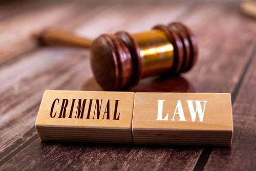 A gavel and blocks spelling criminal law symbolize what a criminal lawyer does.